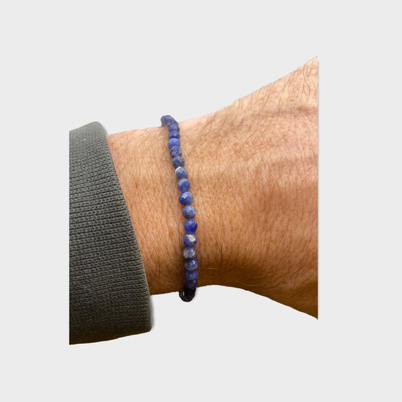 Armbånd med blå perler båret på en persons håndled.